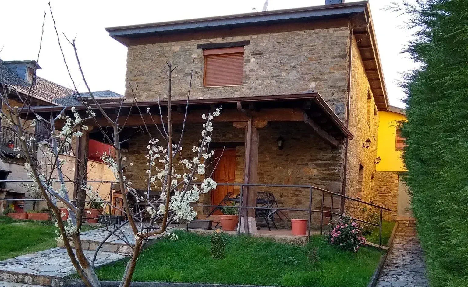 Fachada de piedra de la casa con un cerezo en flor en el jardín
