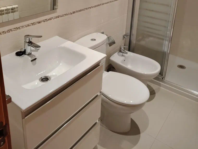 Cuarto de baño con mueble de lavabo, espejo grande, bidé y ducha con mampara
