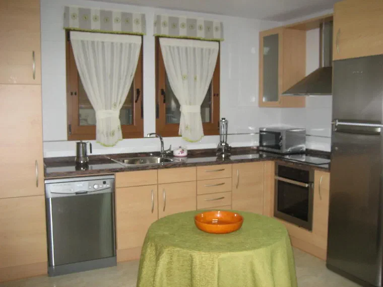 Cocina equipada con lavavajillas, horno, microondas y mesa redonda