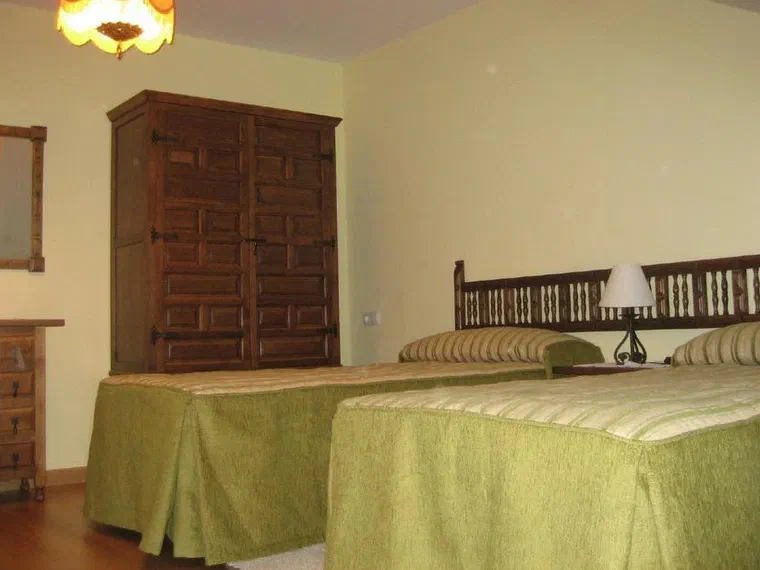 Habitación con dos camas individuales y armario de madera tallada