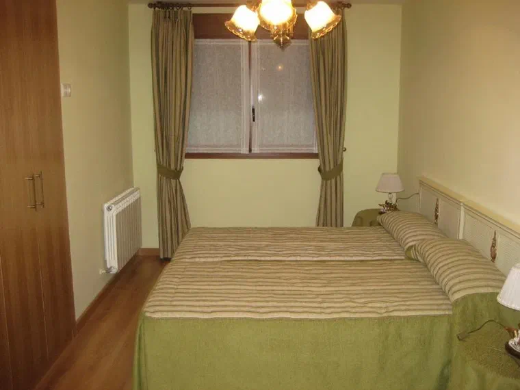Habitación con cama de matrimonio, armario empotrado y ventana al exterior