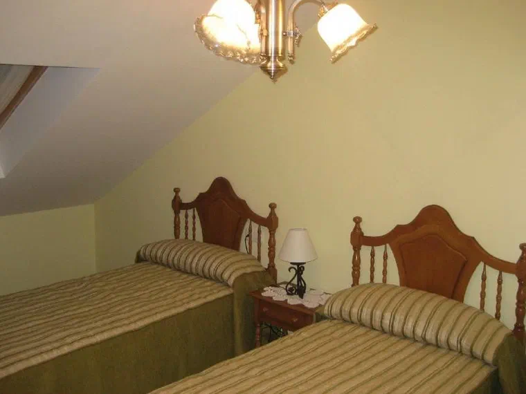 Habitación abuhardillada con dos camas individuales y ventana de tejado
