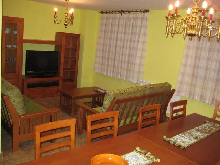Zona de estar con televisión y mesa de comedor de madera